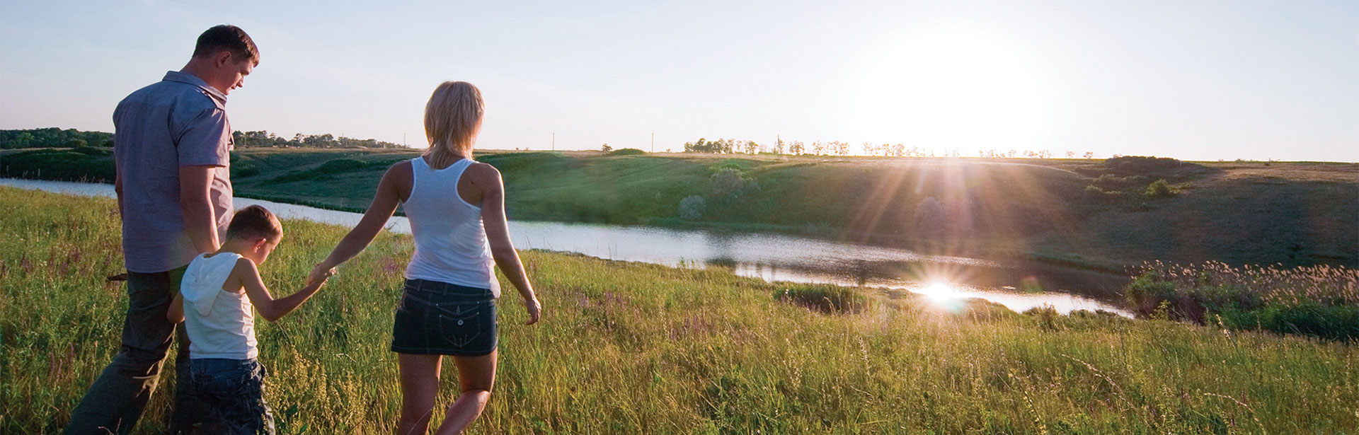 A family walks through a sunlit field at sunset, surrounded by tranquility.